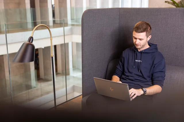 Et billede af Carl Reid i en stol med nissehue og julesweater. I baggrunden står en stak Coolblue-kasser og juletræer.